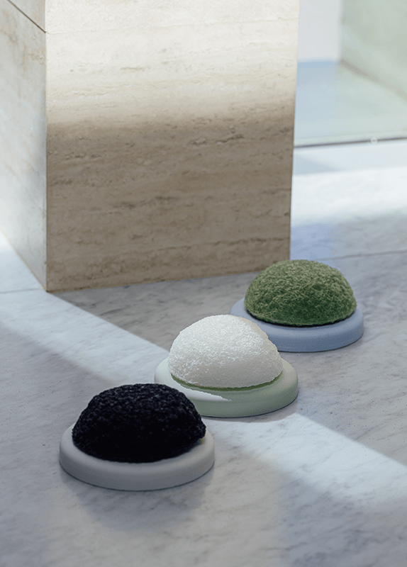 Shikohin Plant-based Konjac sponge trio in white, green, and black colors on a marble surface.