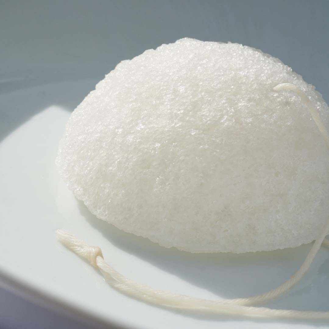 Shikohin Plant-based konjac sponge on a plate, suitable for all skin types, gently exfoliates and refines skin texture.