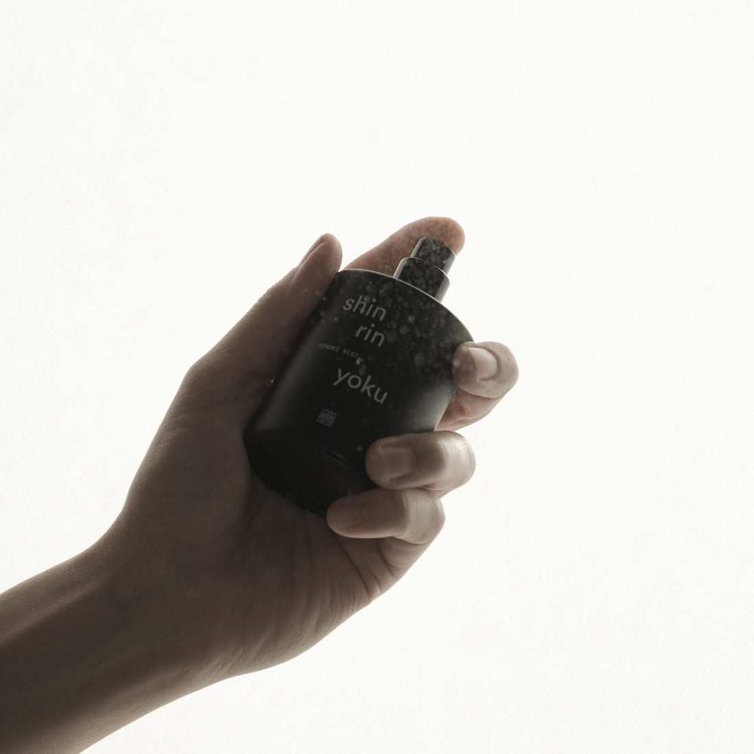 Hand holding Hinoki Mist PM bottle with Japanese hinoki leaf essential oil for relaxation.