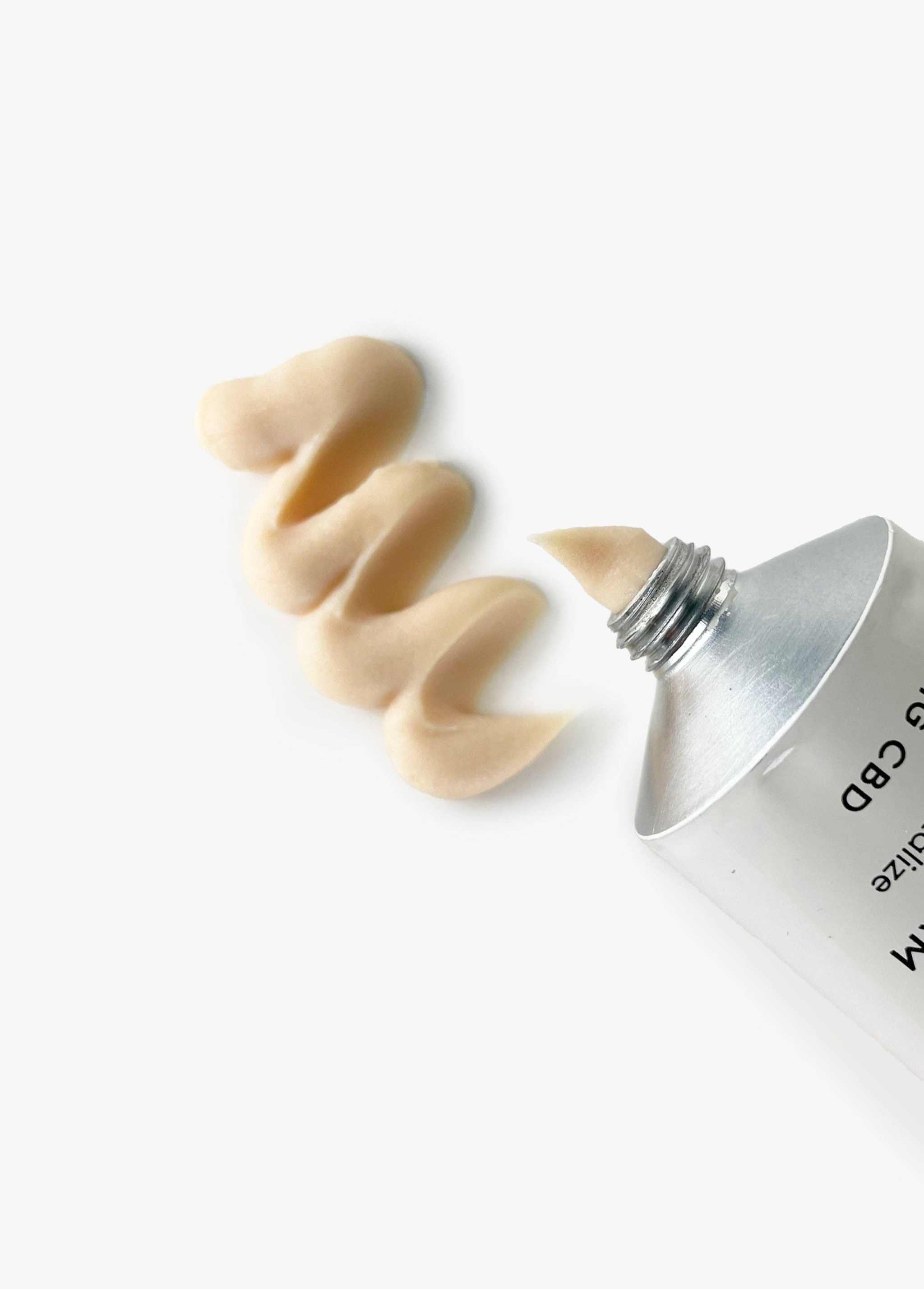 Shikohin Hand & Foot Massage Cream tube with cream swirled on white surface.
