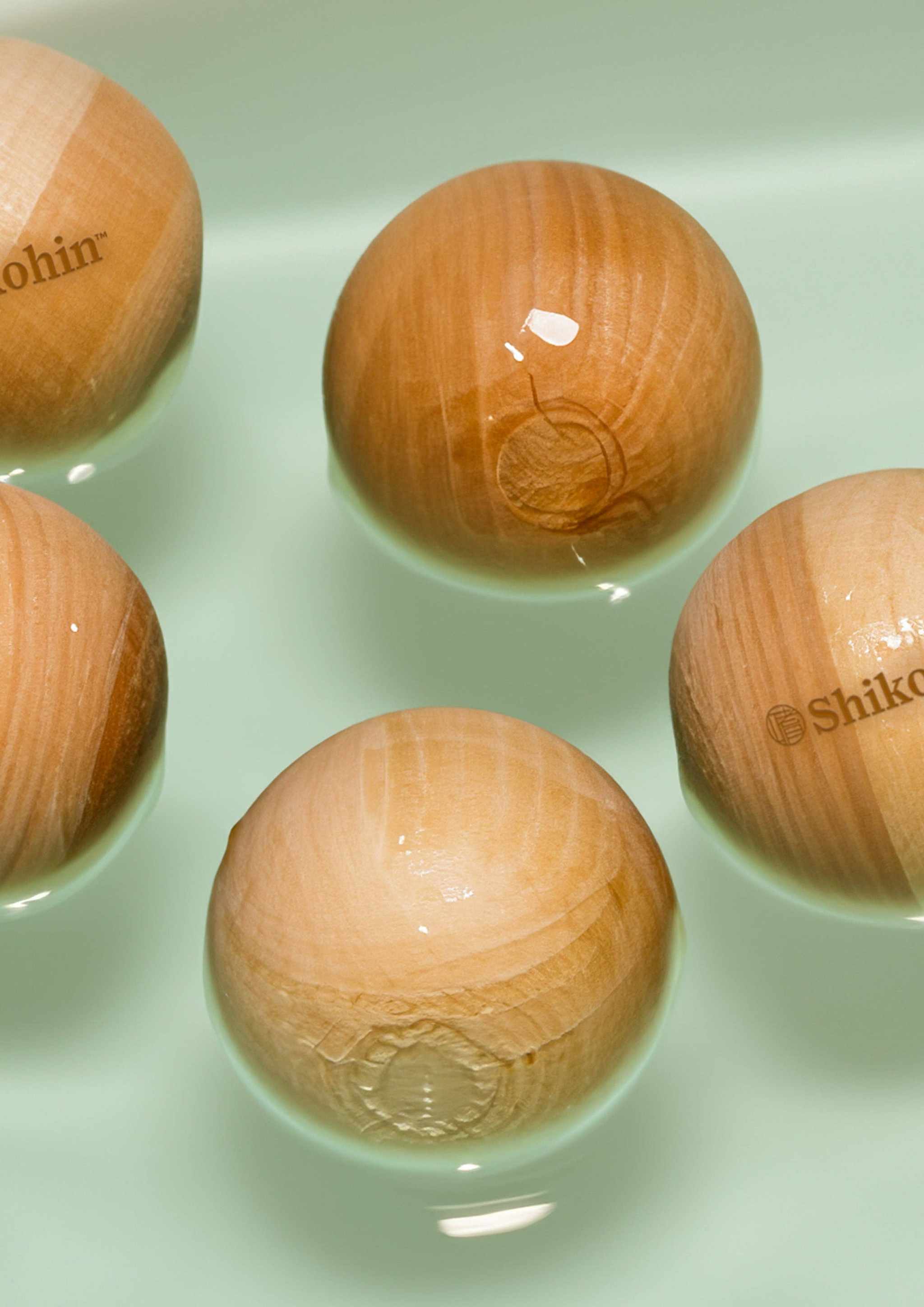 Hinoki bath balls floating in water, showcasing natural wood texture and luxurious aroma.