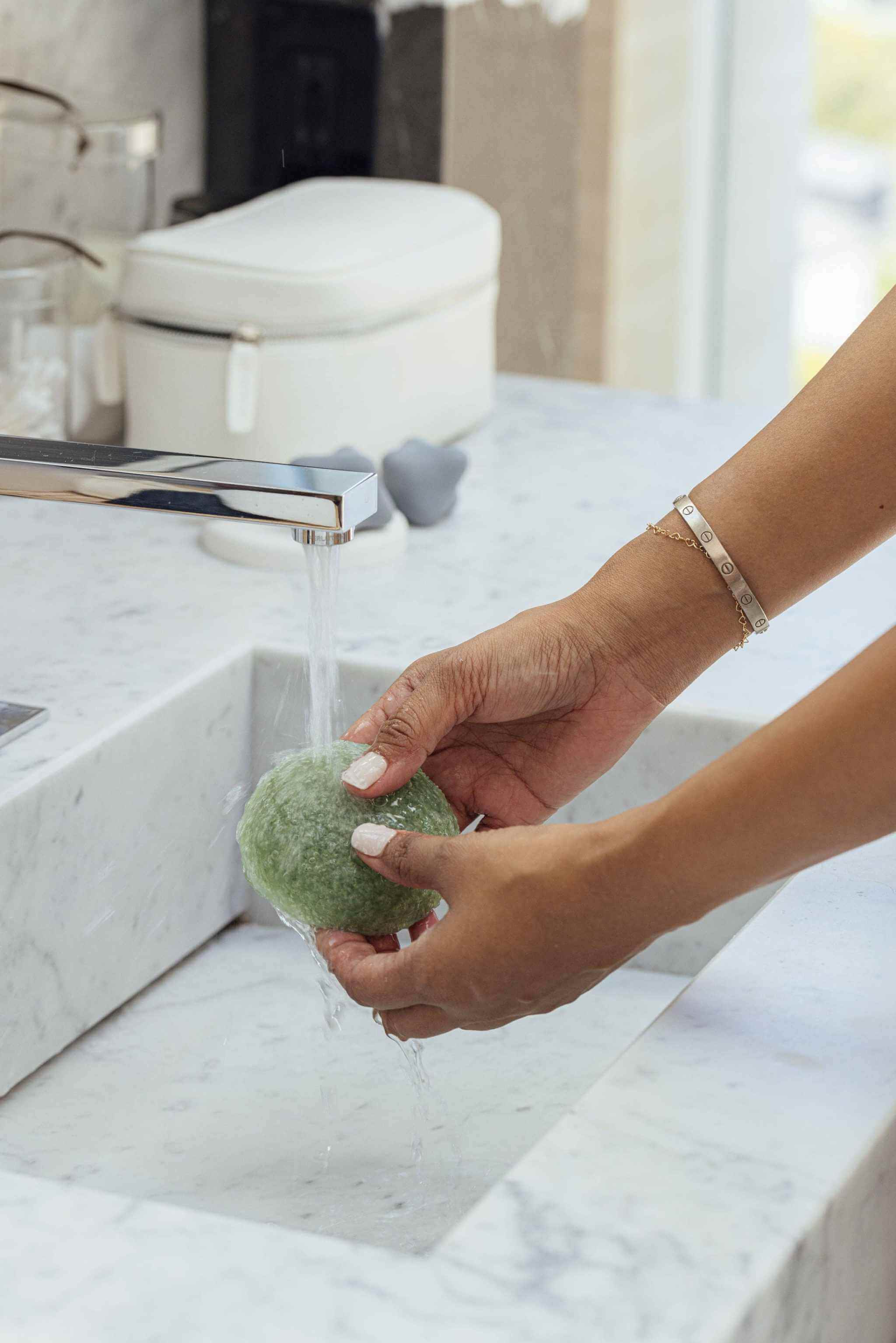 Shikohin Plant-Based Konjac Sponge being rinsed under a faucet, suitable for all skin types.
