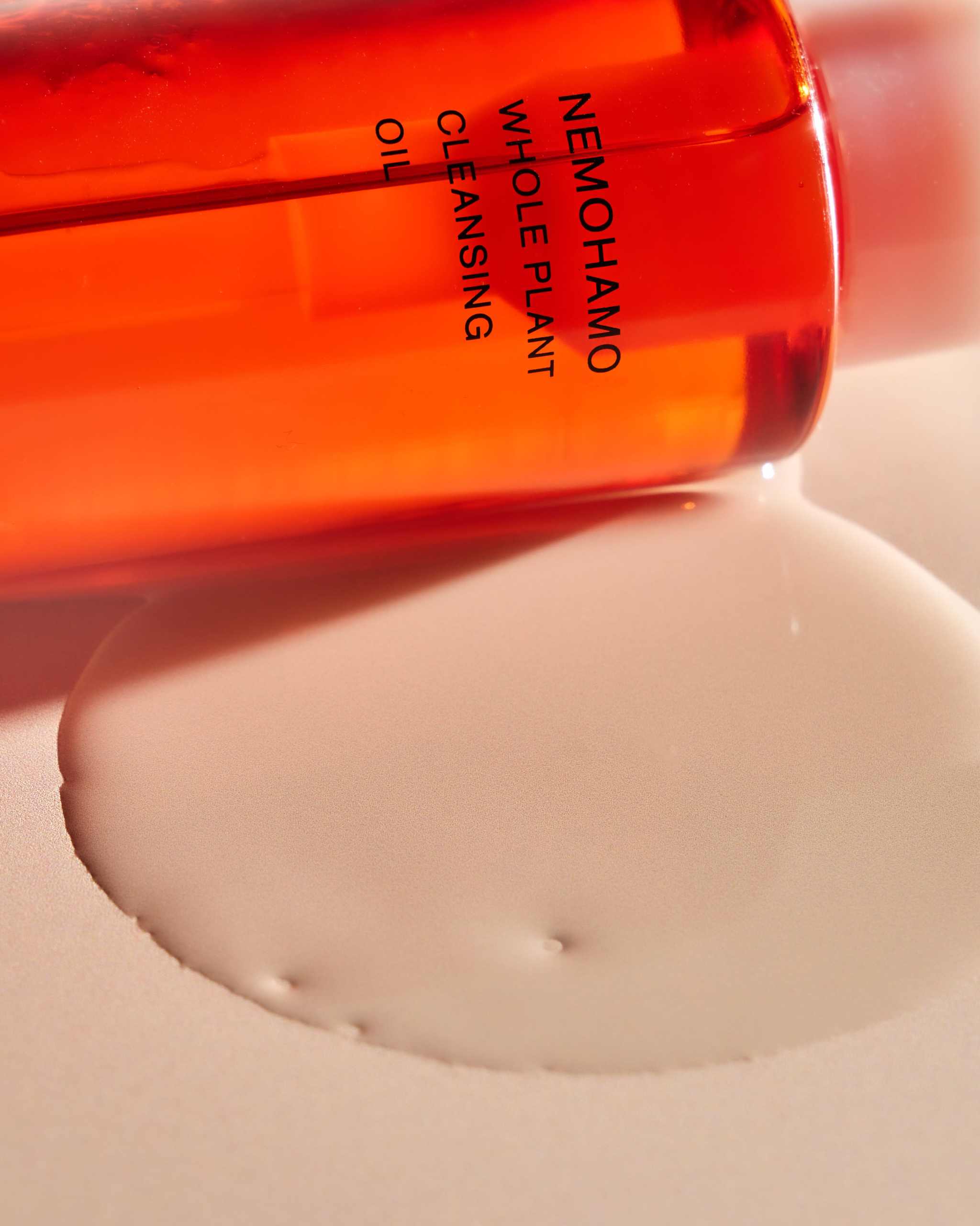 Nutrient-rich NEMOHAMO cleansing oil bottle with spilled oil revealing luminous skin benefits.