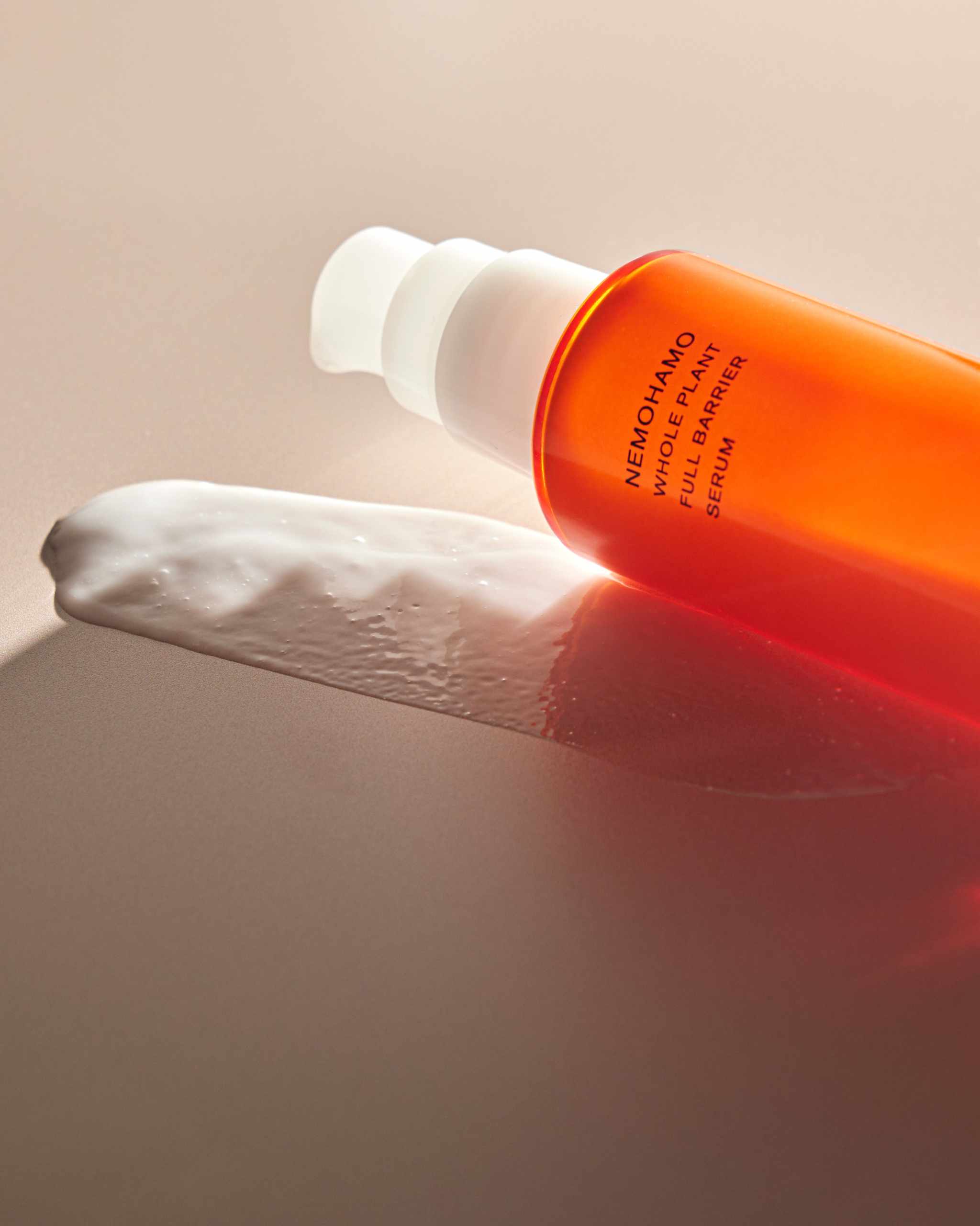 NEMOHAMO Full Barrier Serum bottle on textured surface with creamy texture.