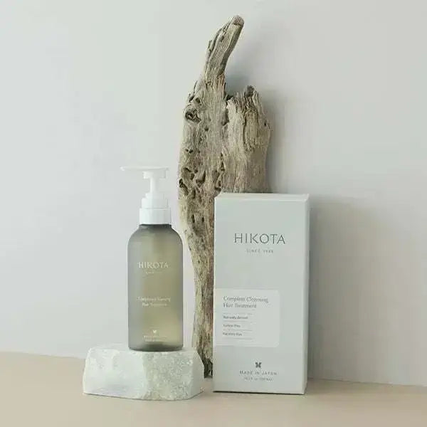 HIKOTA Complete Cleansing Hair Treatment bottle and packaging against driftwood background.