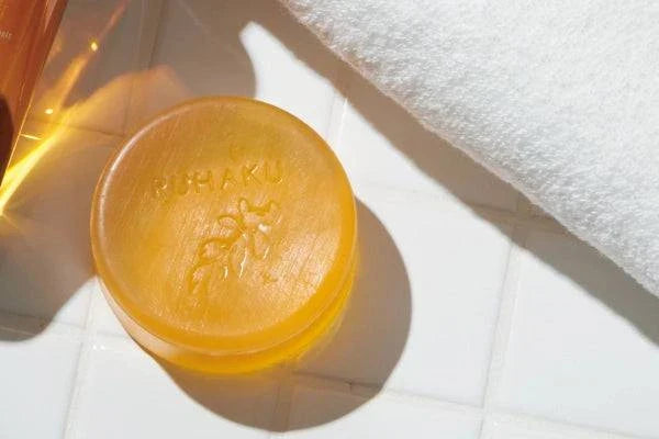 Okinawan Ruhaku Gettou Clear Soap with eco-friendly sea clay and botanical extracts on a white surface.